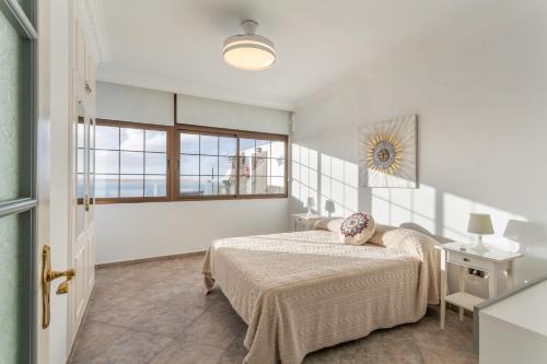 a white bedroom with a bed and a window at Crisol Apartamento in Puerto de la Madera