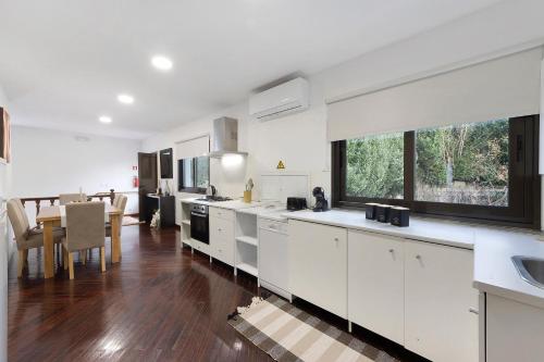 a kitchen with white cabinets and a dining room at Casa São Domingos 1 in Lousada