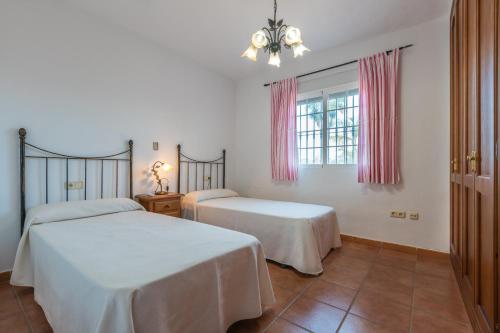 a bedroom with two beds and a window at Chalet andaluz Los Alberos in Coín