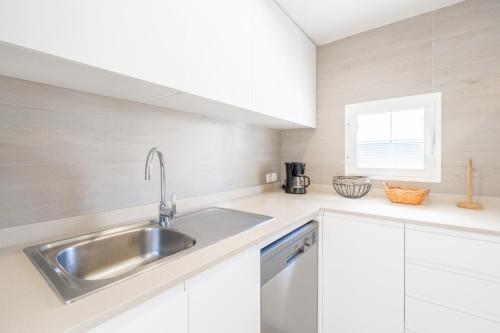 a kitchen with white cabinets and a stainless steel sink at Villa Sam 3 in Can Picafort
