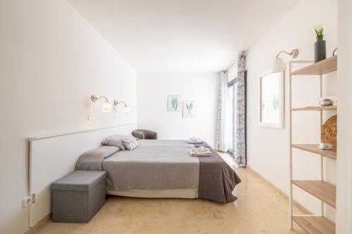 a white bedroom with a bed and a shelf at Villa Sam 3 in Can Picafort