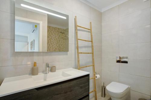 a bathroom with a sink and a toilet and a mirror at Casa Do Tempo com Jacuzzi in Ribeira Brava