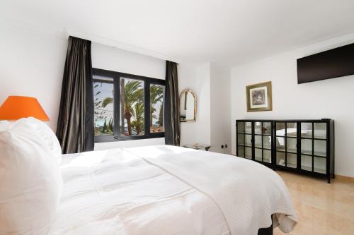 a white bedroom with a large bed and a window at Villa Flores in Marbella