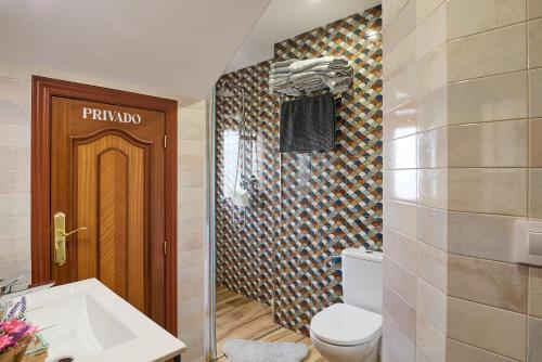 a bathroom with a toilet and a wooden door at Casa Rural Martemma in Zuheros