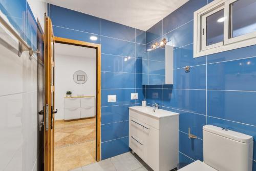 a blue bathroom with a toilet and a sink at Casa Ñico in Artenara