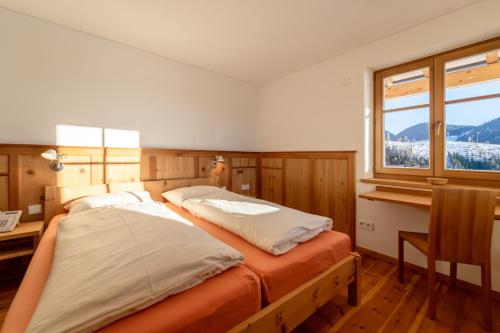 a bedroom with a bed with a desk and a window at Lexn Radein in Redagno