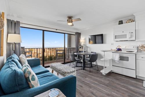 a living room with a blue couch and a kitchen at Boardwalk Breeze Oceanfront Pool Villa in Carolina Beach