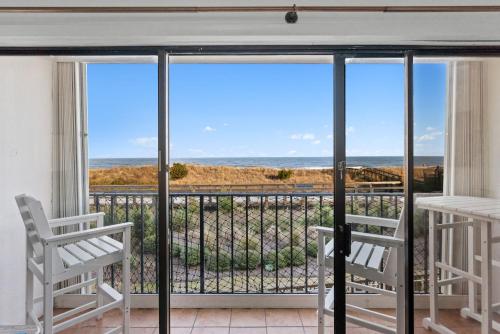 a balcony with two chairs and a view of the ocean at Boardwalk Breeze Oceanfront Pool Villa in Carolina Beach