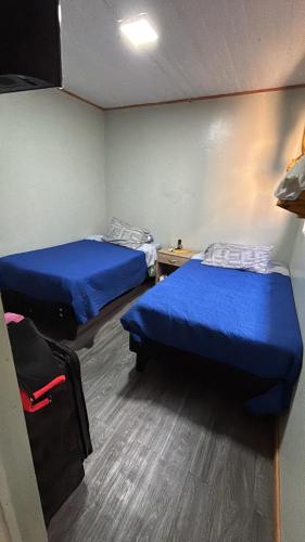 two beds in a room with blue sheets at Cabañas Simón y kiara in Los Vilos