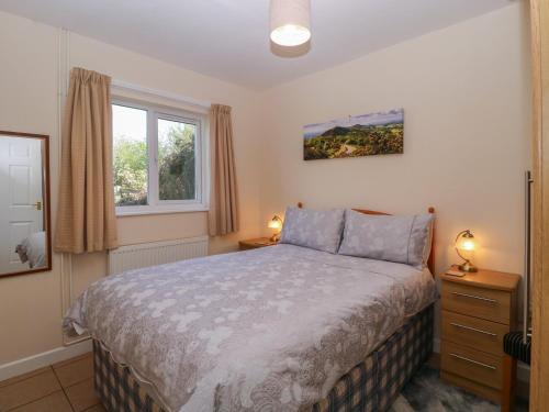 a bedroom with a bed and two lamps and a window at The Turbles - Wagtail in Castlemorton