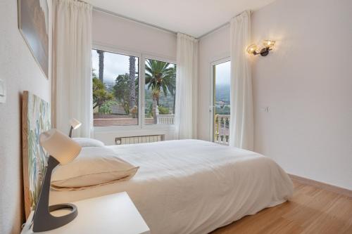 a white bedroom with a large bed and a window at Hiding Place Apartamento Mocan in Los Realejos