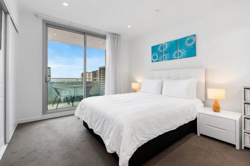a bedroom with a white bed and a large window at Adelaide Central Skyline Panoramic Suite Three in Adelaide