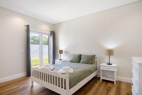 a white bedroom with a bed and a window at Casa D'Avó - Family Coastal Escape in Casa Nova