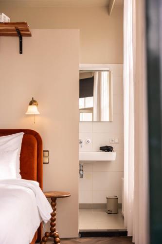 a bedroom with a bed and a sink and a mirror at Hotel By Atelier in Nijmegen
