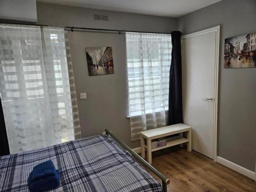 a bedroom with a bed and a table and windows at Cosy Rooms next to St Pancras Station in London