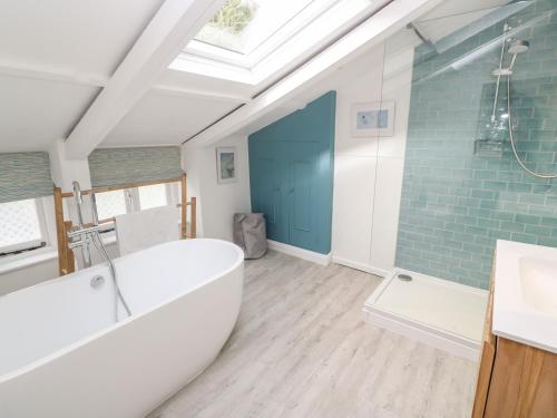 a bathroom with a white tub and a blue wall at Widgeons Keel in Falmouth