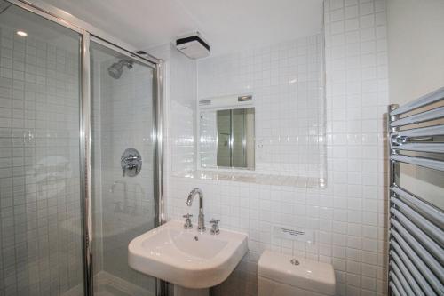 a white bathroom with a sink and a shower at 3 Combehaven in Salcombe