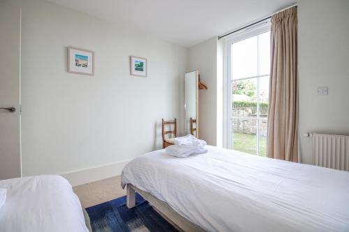 a white bedroom with a bed and a window at 3 Combehaven in Salcombe