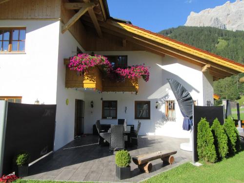 a white house with a patio with flowers on it at Alpen-Chalet Ehrwald in Ehrwald