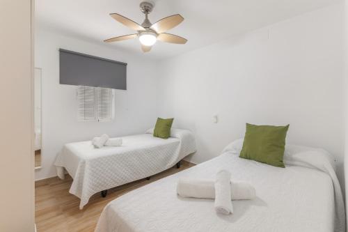 a white room with two beds and a ceiling fan at Encanto Costero in Ayamonte