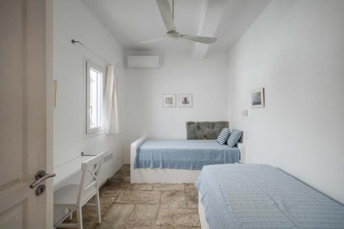 a white bedroom with a bed and a desk at House Avlomonas in Livadi