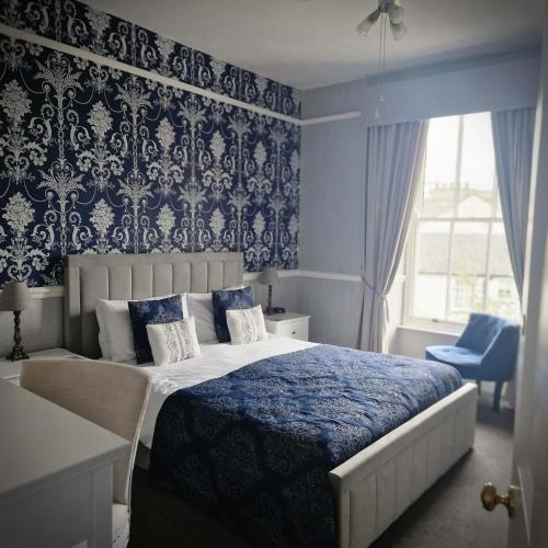 a bedroom with a large bed with a blue patterned wall at New Hall Bank in Bowness-on-Windermere