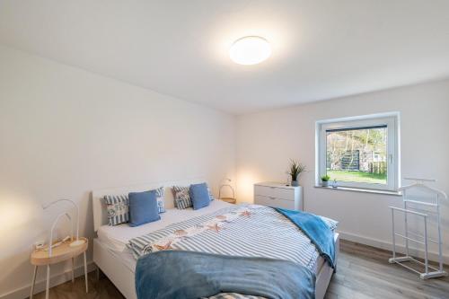 a white bedroom with a bed and a window at Strandnahe Fewo 1 in Dierhagen