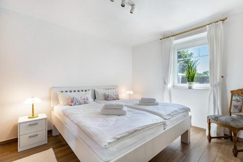 a white bedroom with a large bed and a window at Ferienhaus Christine in Breklum