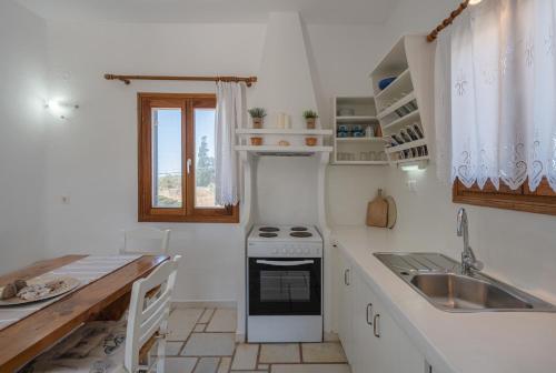 a white kitchen with a stove and a sink at Maria's Village Suite in Kampos Paros