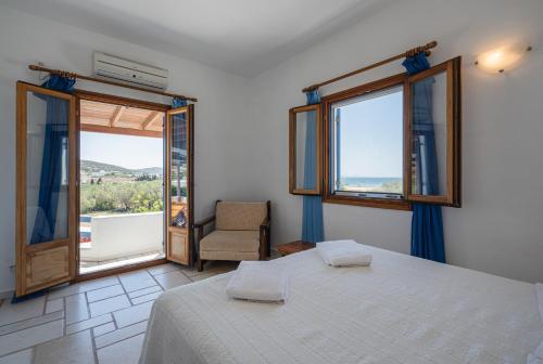 a bedroom with a bed and a chair and windows at Maria's Village Suite in Kampos Paros