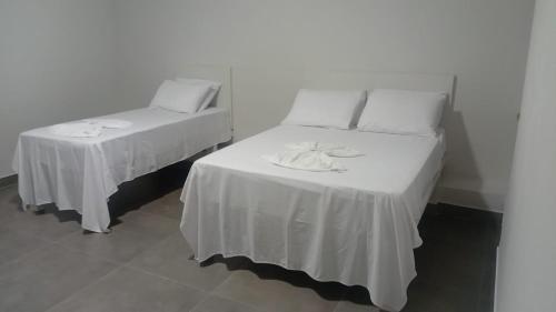 a bedroom with two beds with white sheets and napkins at Hotel AG3 in Teixeira de Freitas
