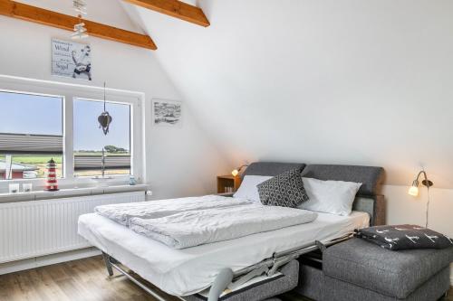 a bed and a chair in a room with a window at Huus achtern Diek - Ferienwohnung 5 in Nordstrand