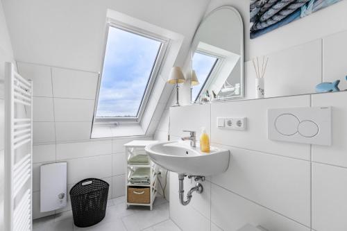 a white bathroom with a sink and two windows at Huus achtern Diek - Ferienwohnung 5 in Nordstrand