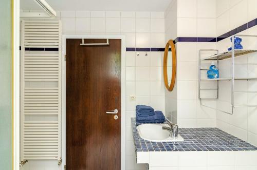 a bathroom with a sink and a wooden door at Fewo3 Buppeape Saterland in Bollingen