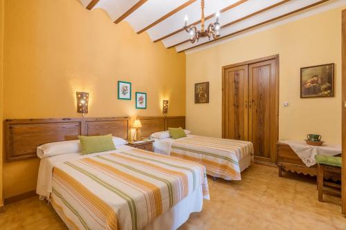 two beds in a room with yellow walls at Lavanda in Hinojares