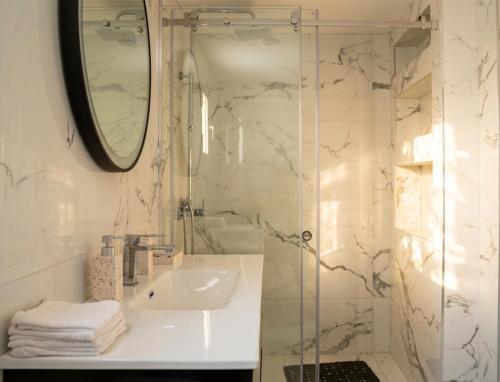 a bathroom with a sink and a shower with a mirror at The Beach White House - 80m from the Beach - Renovated in Áyios Yeóryios