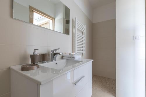 a white bathroom with a sink and a mirror at Villa Bumortu in Olmeto