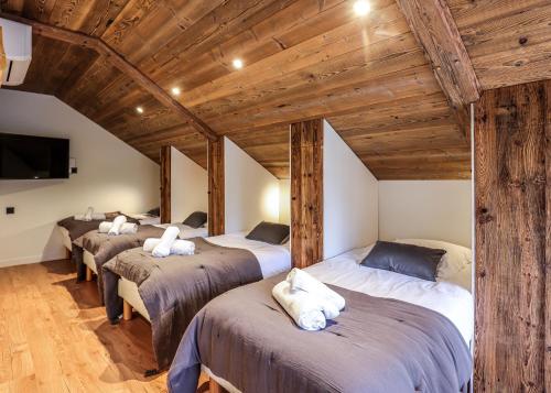 Eine Reihe von vier Betten in einem Zimmer mit Holzdecke in der Unterkunft Laltizoard in Briançon