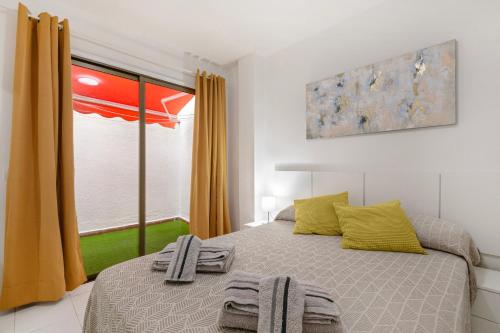 a bedroom with a bed with yellow curtains and a window at Apartamento El Tute in Bajamar