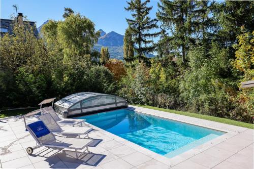 ein Swimmingpool mit zwei Liegestühlen und einem Glashaus in der Unterkunft Laltizoard in Briançon