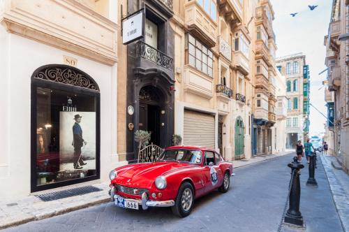 a red car parked on a street in front of a store at Casa Ellul - Small Luxury Hotels of the World in Valletta
