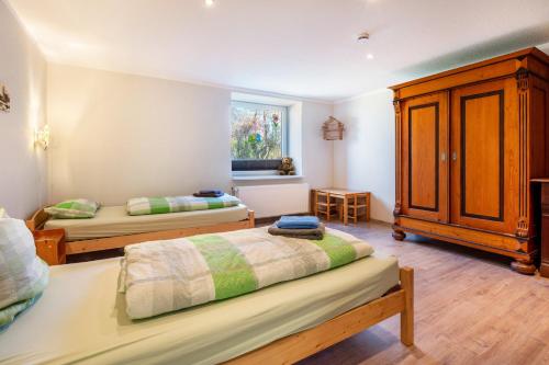 a bedroom with two beds and a wooden cabinet at Fewo Heimathafen in Osterbruch