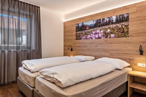 two beds in a room with a large window at Aster Moments Apt Moritz in San Genesio Atesino