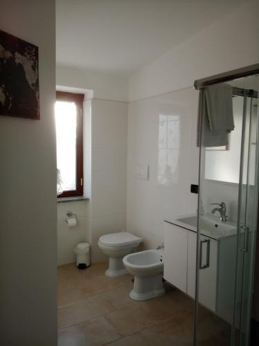 a white bathroom with a toilet and a sink at I 4 mori in Fiumicino