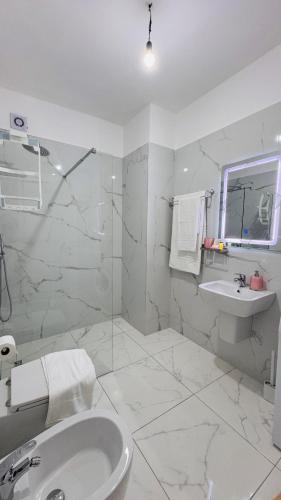 a white bathroom with a sink and a shower at Eddy's Luxury Suites - Ilyonis in Shëngjin