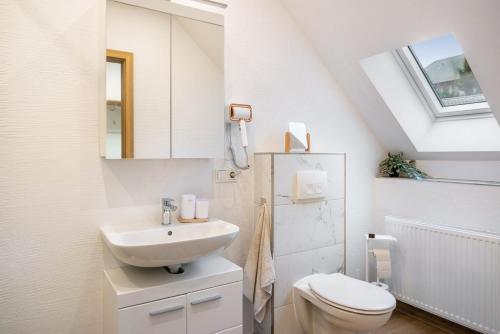 a white bathroom with a sink and a toilet at Ferienwohnung Maxim in Saarburg