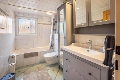 a bathroom with a sink and a toilet and a tub at Ferienwohnung Krempermoor 1 in Krempermoor