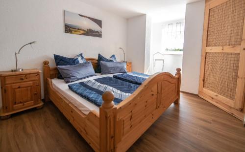 a bedroom with a wooden bed with blue pillows at Scheidegg unterm Kreuzberg in Scheidegg