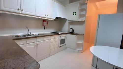 a kitchen with white cabinets and a sink and a table at Ocean and River Torreira in Torreira