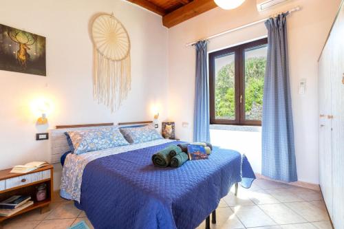 a bedroom with a bed with blue sheets and a window at Hakéyah in Castelsardo
